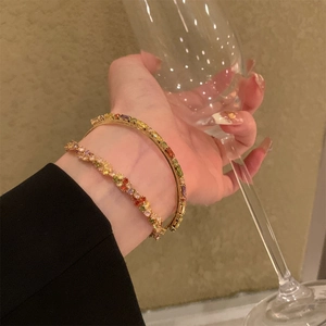 Dettaglio di un set di bracciali dorati con gemme colorate a gradiente di alta qualità