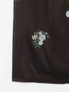 Gros plan détaillé de broderies florales avec perles blanches et sequins verts sur satin noir