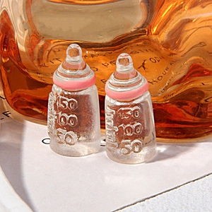 Detail of two miniature resin baby bottles with pink rings and molded scale markings