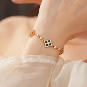 Détail d'un bracelet ajustable plaqué or avec trèfle en zircon et pierre carrée verte