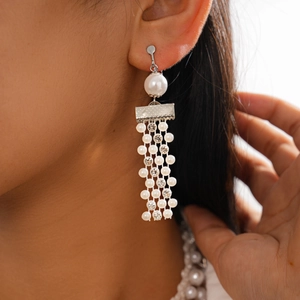 Detail of elegant pearl and rhinestone tassel earrings with spiral clip-on mechanism