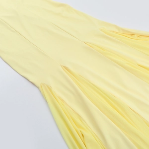 Détail de l'ourlet plissé de la robe jaune montrant la texture du tissu de qualité