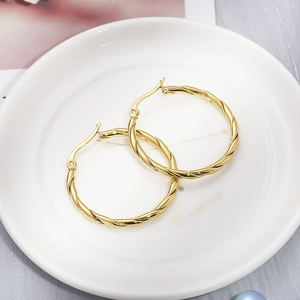 Detail shot of 30mm gold twisted rope texture hoop earrings on a ceramic display tray