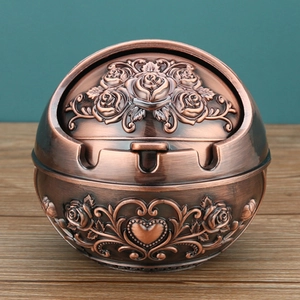 Detailed macro shot of bronze-finished metal ashtray with rose and heart embossed patterns