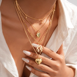 Detail of layered gold necklace featuring heart pendants and circular world map charm