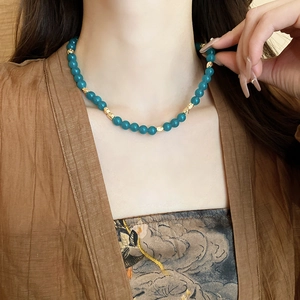 Detail of vintage beaded necklace with teal stones and golden engraved metal spacers