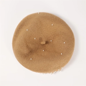 Close-up of camel cashmere beret with elegant white pearl bead embellishments