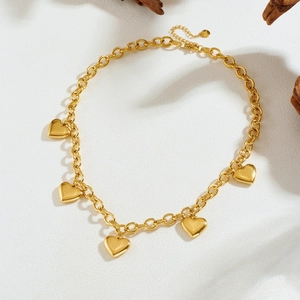 Gold plated stainless steel necklace with five heart pendants on textured background