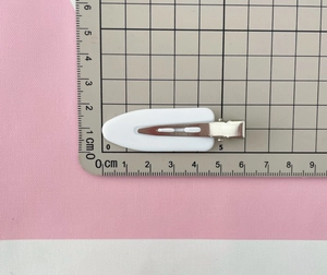 Mesure à plat d'une pince à cheveux blanche montrant une longueur de 6 cm sur règle