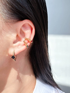 Close-up of gold chain ear cuffs and dangle earring with black and red crystals