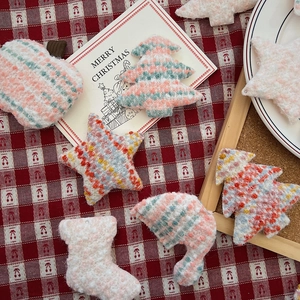 Flat lay of colorful knitted Christmas ornaments like stars and trees on a festive cloth