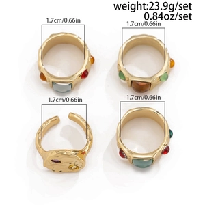 Set of four gold geometric rings with colorful gemstones and irregular metal textures