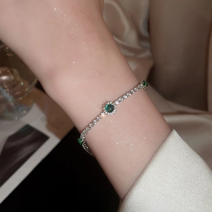 Gros plan d'un bracelet de luxe argenté avec zircon vert et cristaux blancs brillants