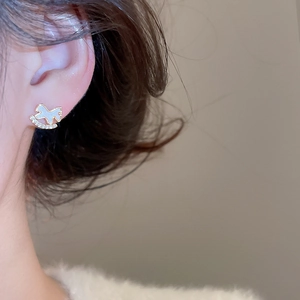 Gros plan d'une boucle d'oreille cheval à bascule dorée avec zircons portée à l'oreille