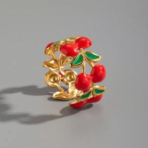 Detailed macro shot of a cherry-shaped enamel ring with green leaf and gold vine details