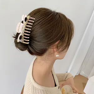 Detailed view of a large iridescent claw clip styled on a woman's hair in a half-up bun