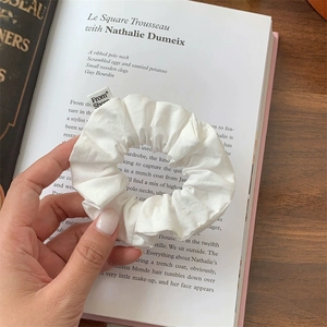 Close-up of a white cotton scrunchie on a magazine page showing soft fabric texture