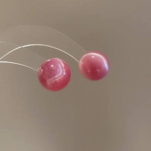 Macro detail of pink opalescent spherical stud earrings with high gloss finish