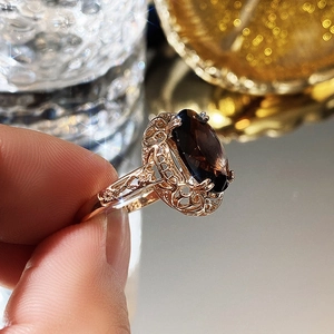 Close-up of vintage rose gold ring featuring intricate hollow floral design and brown zircon