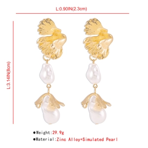 Detailed close-up showing long baroque pearl earrings with golden shell-textured alloy