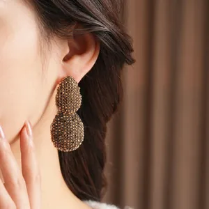 Vintage gold oval drop earrings with textured crystal pavé on a model for elegant look