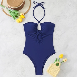 Maillot de bain une pièce sexy bleu foncé avec découpes et licou sur fond de marbre