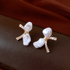 Close-up of 18k gold plated bow earrings with baroque pearls and sparkling zircons
