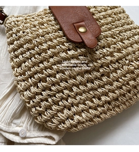 Close-up of woven straw texture with brown leather flap and vintage gold buckle