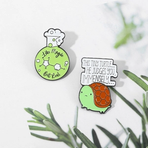 Detail of green flask and turtle enamel pins with Like Magic But Real text on white background