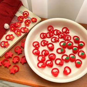 Detail view of red festive hair tie set featuring strawberry and heart charms for kids