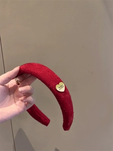 Detailed view of a red velvet padded headband with a gold heart pendant and engraving