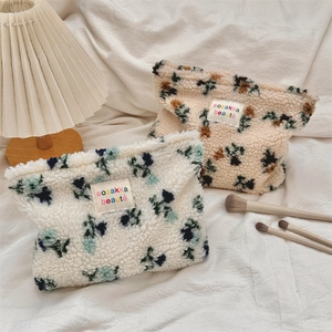 Close-up of floral plush makeup bags with sozakka beauté label and zipper detail