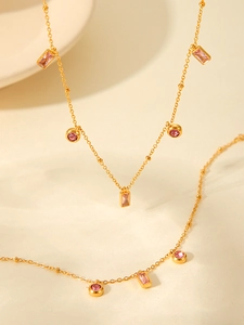 Detailed close-up of 18K gold-plated chain with pink rectangular and round zircon pendants