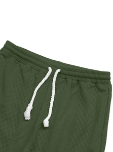 Detail of dark green waffle knit joggers featuring elastic waist and white drawcord