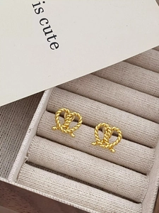 Detailed macro view of gold-finished S925 silver knot earrings in a velvet jewelry box