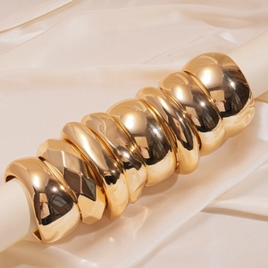 Polished chunky gold geometric acrylic bangles on minimalist display stand