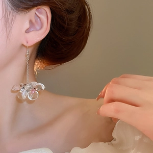 Close-up of transparent acrylic flower drop earrings with pink bead and metal tassels
