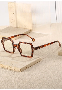 Detail of tortoise shell square frame glasses displayed on a stone architectural pedestal