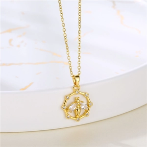 Détail du collier abeille doré avec zircons brillants sur plat en marbre