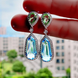 Close-up of bicolor crystal drop earrings featuring pear-cut green and blue stones