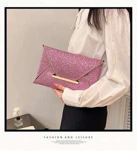 Pochette enveloppe rose pailletée avec fermeture en métal doré portée par mannequin