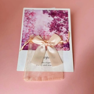 Detailed close-up of pink organza gift bag with a satin ribbon bow on floral card