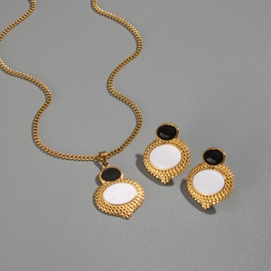 Dettagli di un set di collana e orecchini dorati con pietre ovali bianche e nere