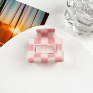 Close-up of pink checkered claw clip on white ceramic plate with a minimalist aesthetic