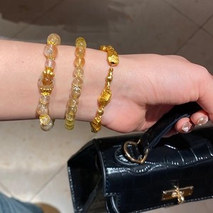 Detailed shot of yellow citrine and rutilated quartz bracelets with gold metal beads