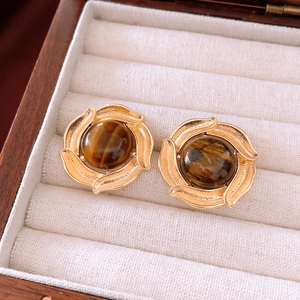 Macro detail of vintage gold hoop earrings featuring brown tiger eye stones in jewelry box