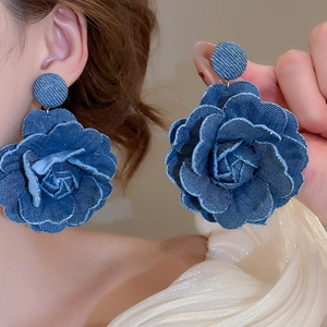 Detail shot of the layered dark blue denim fabric flower earring with 3D texture and petals