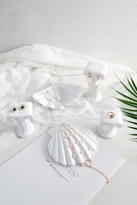 White resin jewelry display set with Greek pillars and shell trays on elegant lace