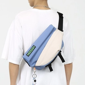 Detail of blue and white sling bag with astronaut charm and adjustable strap