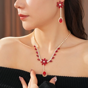 Detail of model wearing red gemstone flower necklace and teardrop earrings in gold finish